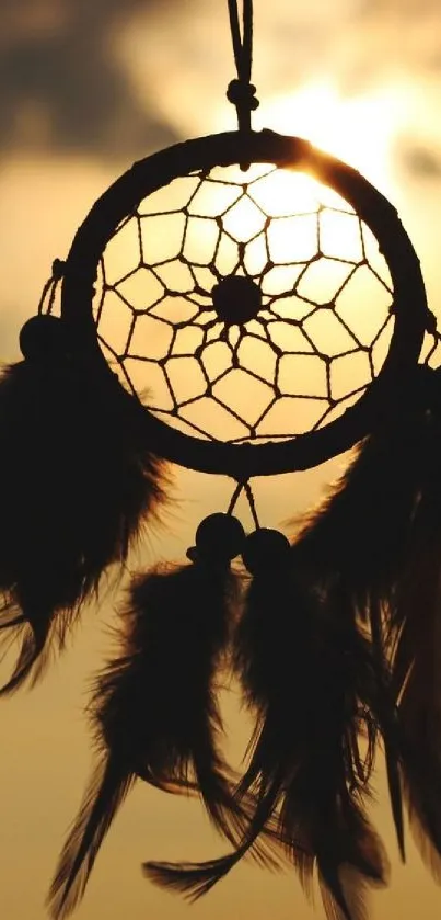 Silhouette of a dreamcatcher against a golden sunset.