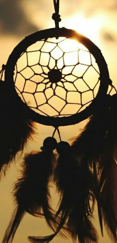 Silhouette of a dreamcatcher against a sunset sky.