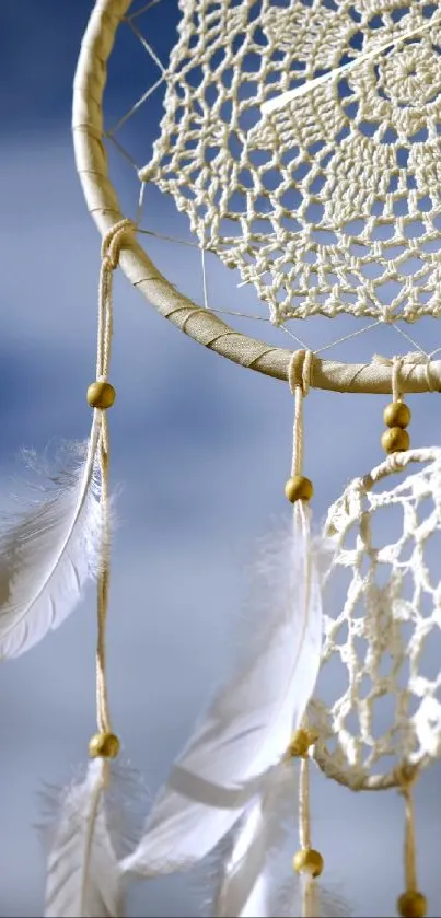Dreamcatcher with feathers against blue sky.