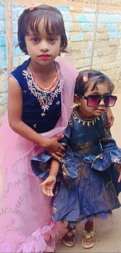 Two young children in colorful dresses posing outdoors