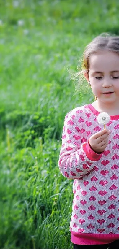 Child holding a dandelion in a vibrant green field.