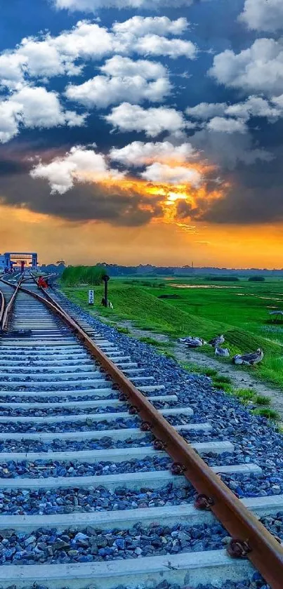 Train tracks leading into a colorful sunset with a vibrant blue sky.