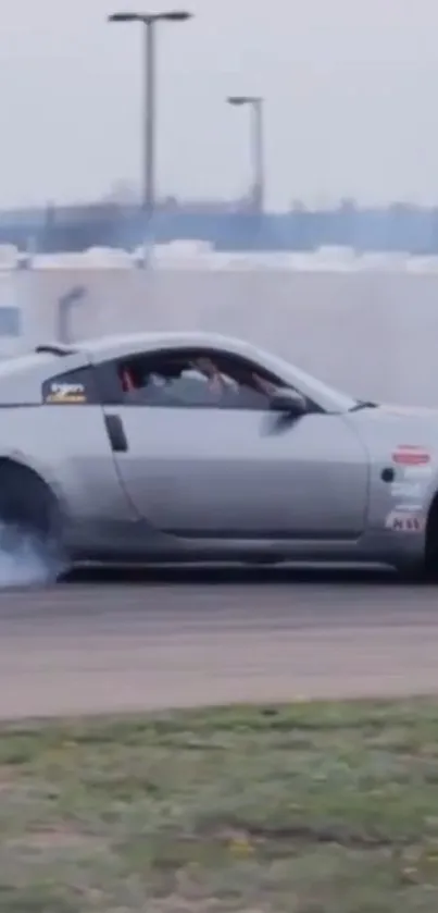 Gray sports car drifting on track with smoke trails.