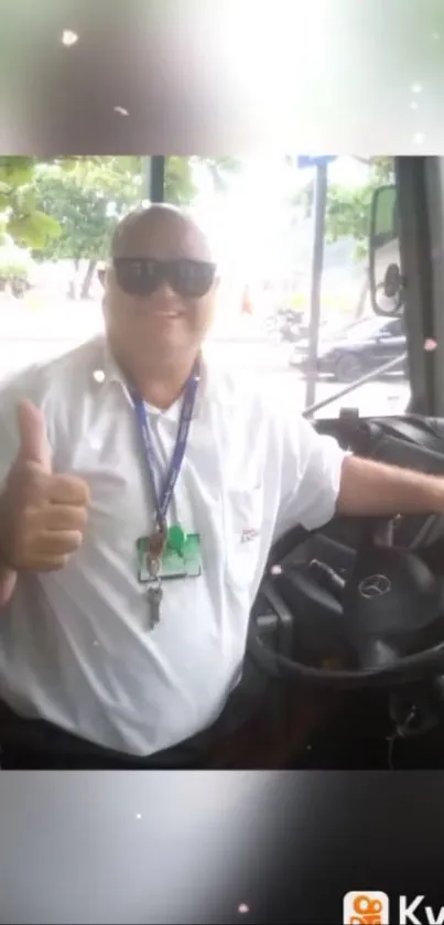 Smiling bus driver gives thumbs up in bright outdoor setting.