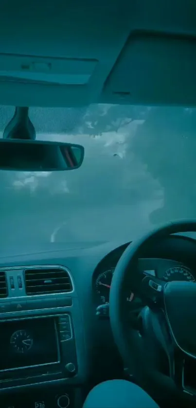 Car interior driving view with misty road ambiance in teal colors.