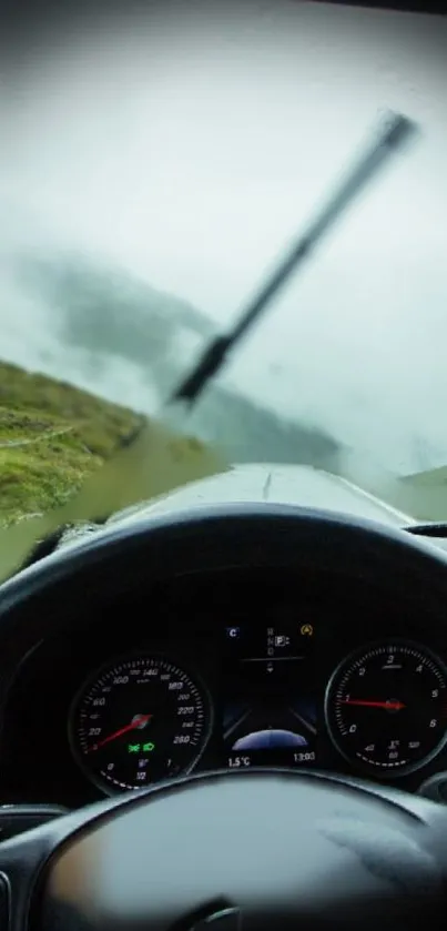 Driving through misty mountain scenery with rain and clouds.