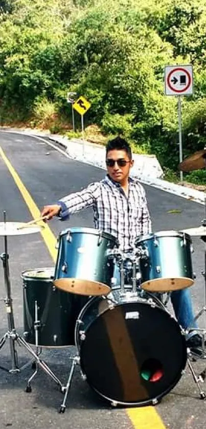 Drummer playing on scenic road surrounded by nature.