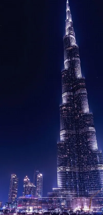 Night view of the Dubai skyline with Burj Khalifa illuminated in blue.