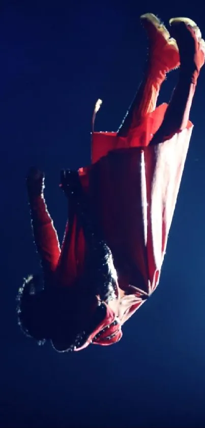 Acrobatic performer in vibrant red attire against a dark background.