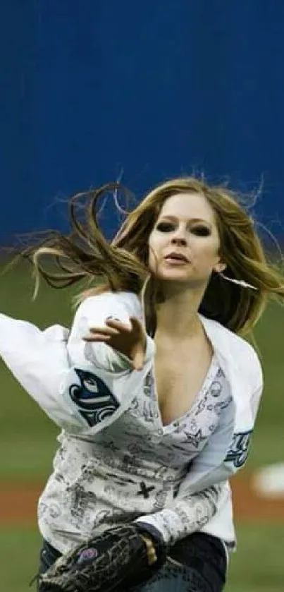 Woman throwing baseball with intensity on field, blue background.