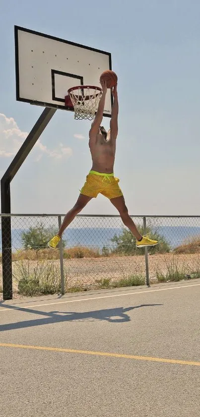 Basketball player jumping to the hoop in bright outdoor setting.