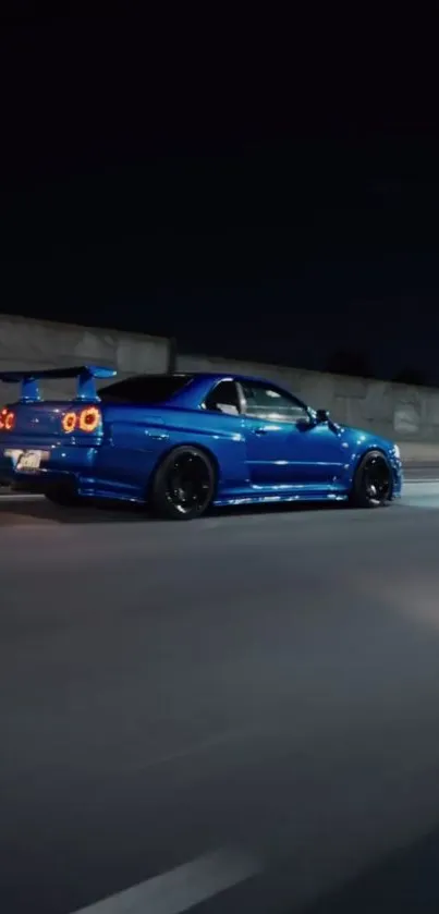 Blue sports car racing through city night on highway.