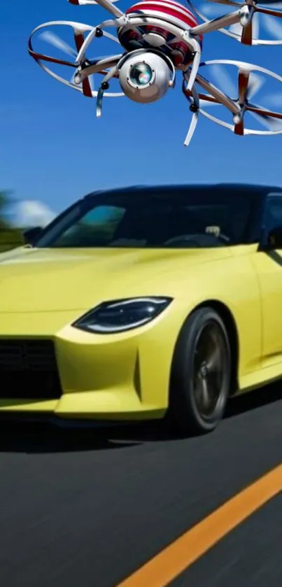 Yellow car racing under a hovering drone against a clear blue sky.