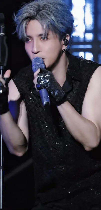 Concert performer with mic on stage with black attire and gloves.