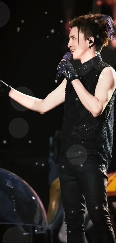 Energetic concert performer in dynamic stage pose with black outfit and gloves.