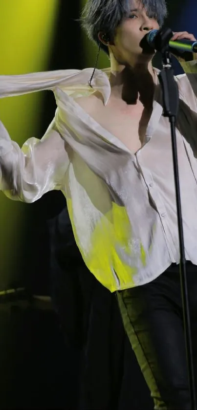 Performer on stage with microphone under colorful lighting.