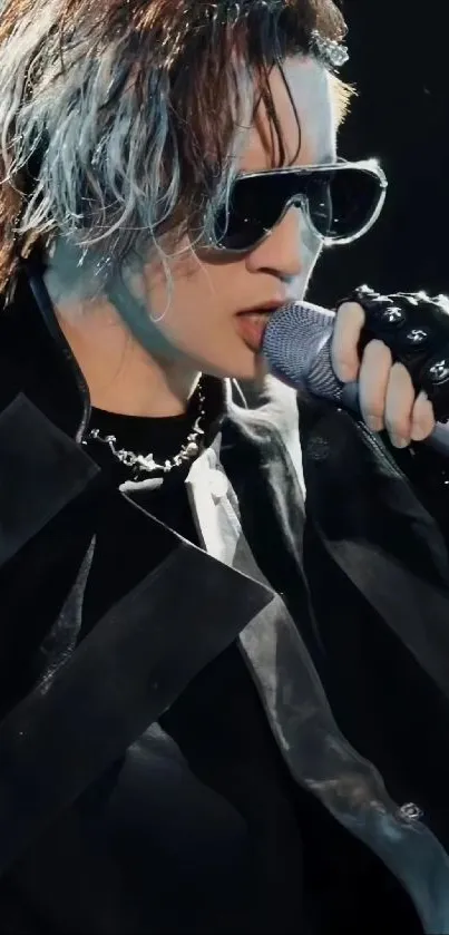 Stylish singer performing live on stage with sunglasses and microphone.