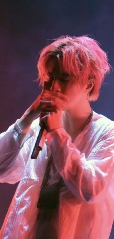 Singer performing passionately under pink stage lights.