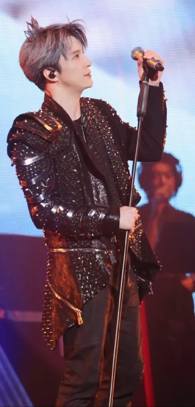 Charismatic performer in studded attire on stage, holding a microphone.