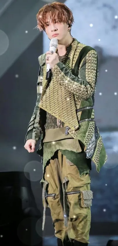 Performer in olive green attire on stage wallpaper.