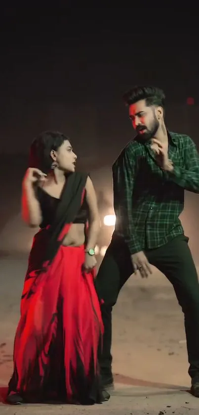 Energetic dance duo in red and black under dramatic lighting.