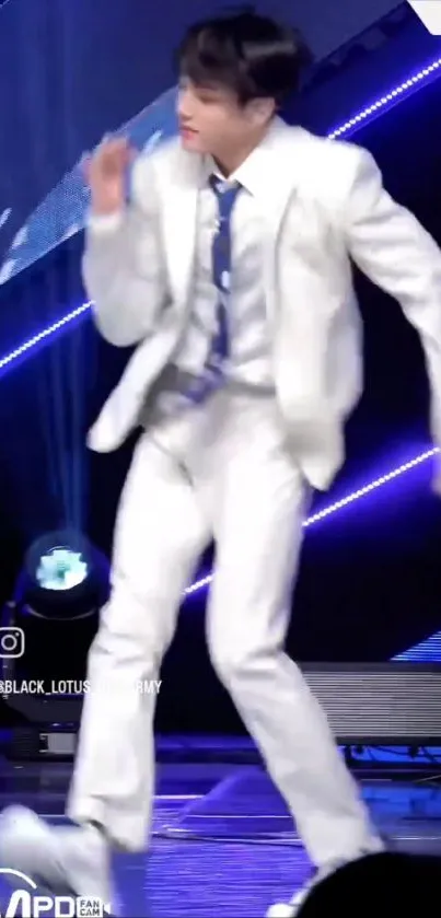 Energetic dancer in white suit on stage with neon lights.