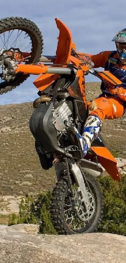 Dirt bike performing a stunt on rocky terrain with scenic background.