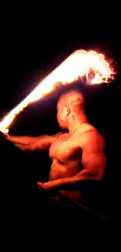 Man performing with fiery torch against black background.