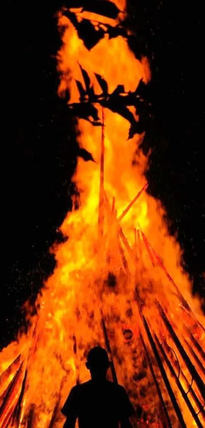 Silhouette in front of blazing orange fire at night.