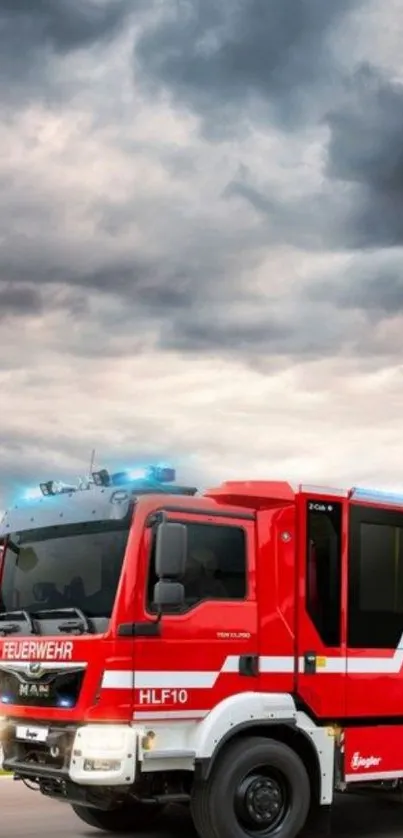 Red fire truck driving under stormy sky.