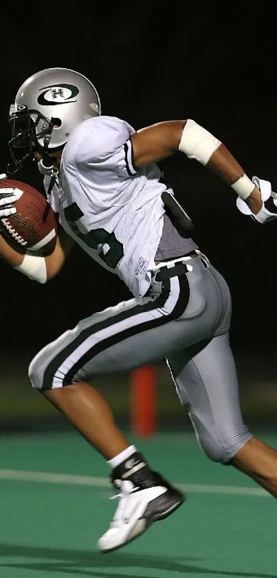 Football player sprinting on green field at night.