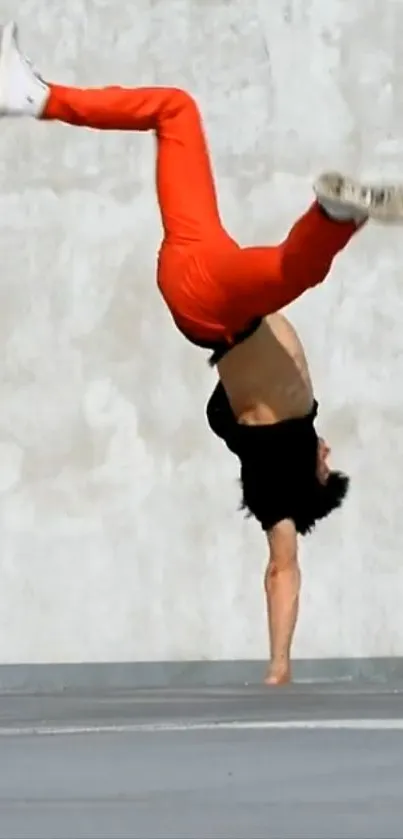 Person performing a handstand in red pants on concrete.