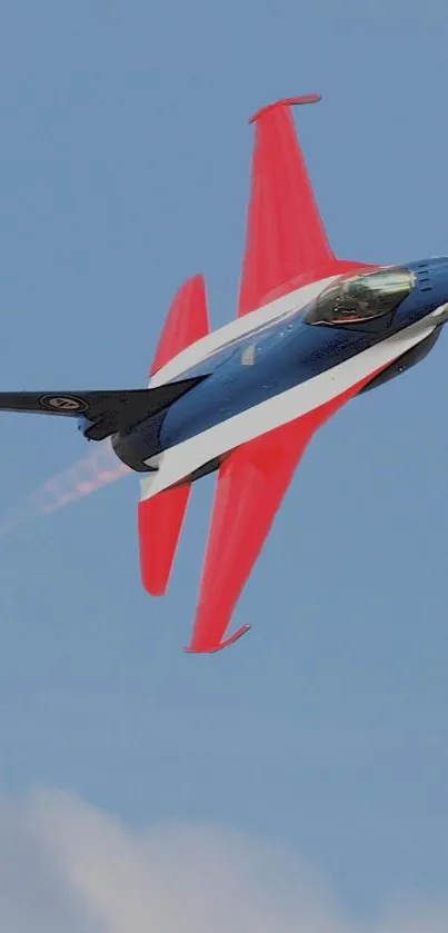 Jet with vibrant red wings soaring in a clear blue sky.