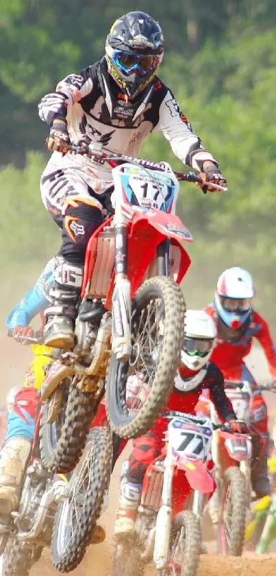 Motocross riders in action on a dirt track amid dust.