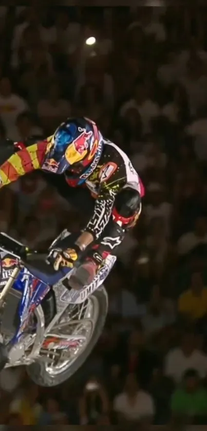 Motocross rider performing stunt in mid-air at night event.