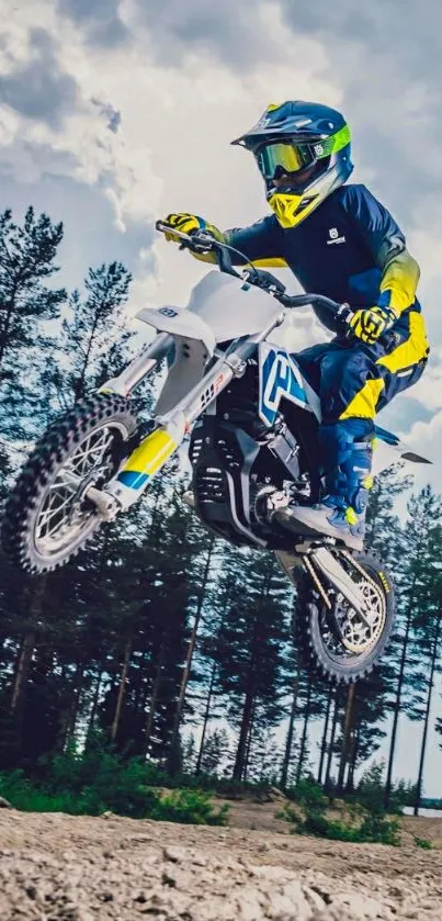 Motocross rider jumps high with forest background in dynamic mobile wallpaper.