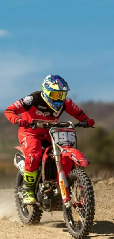 Motocross racer in vibrant red gear, speeding across a dirt track.