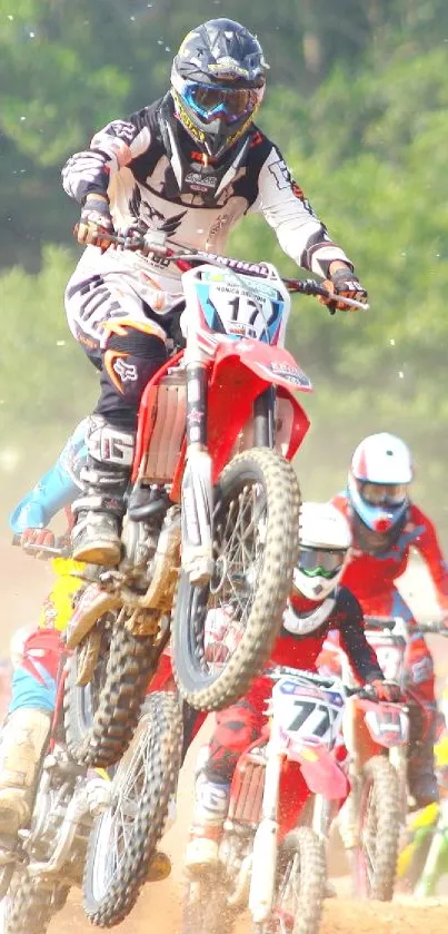 Motocross riders in action, mid-jump on dirt track.