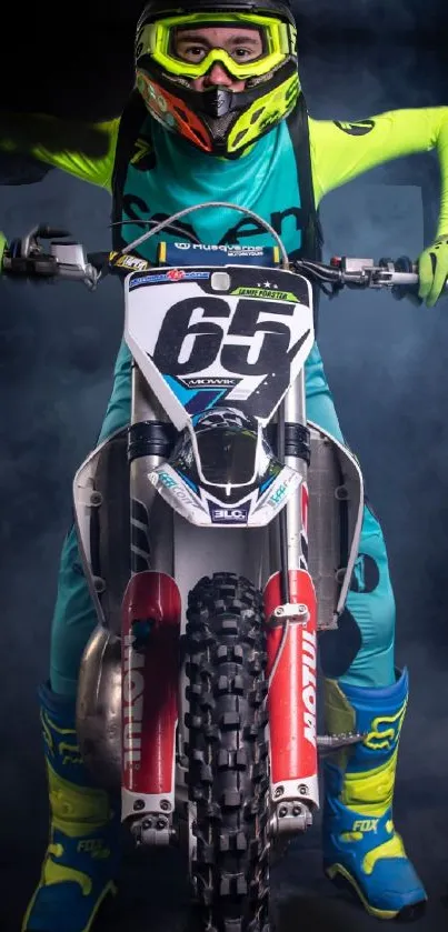 Motocross rider in vibrant gear on a smoky blue background, ready for action.