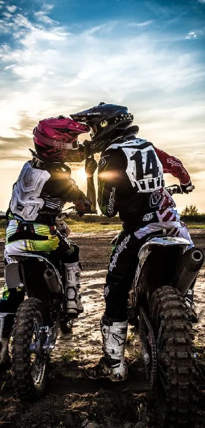 Motocross riders at sunset, set against a vibrant blue and orange sky.