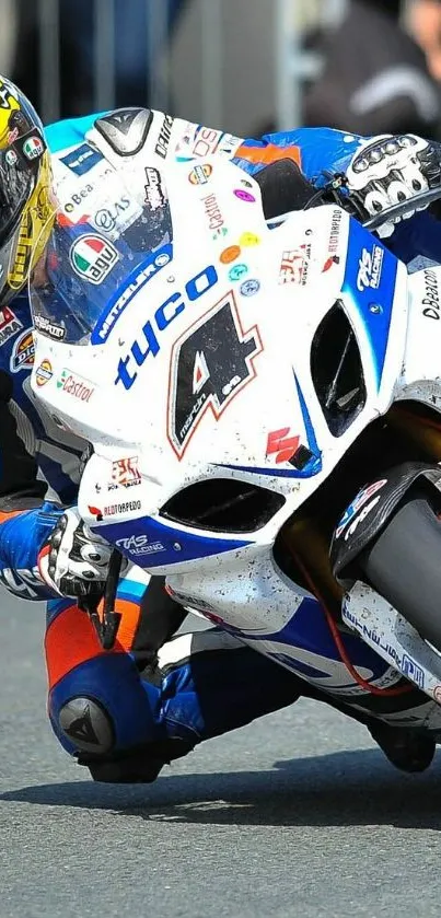 Motorcycle racer in action on a blue and white bike during a high-speed turn.