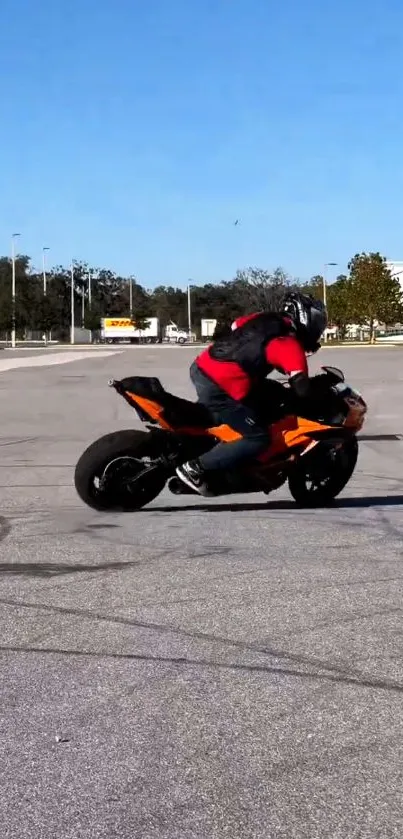 Motorcyclist performs a thrilling stunt on an orange bike in an open area.