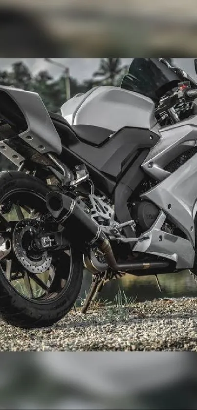 Sleek gray sportbike parked on gravel with a scenic backdrop.