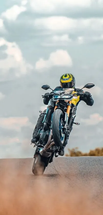 Motorcycle performing a wheelie on a open road with a cloudy sky backdrop.