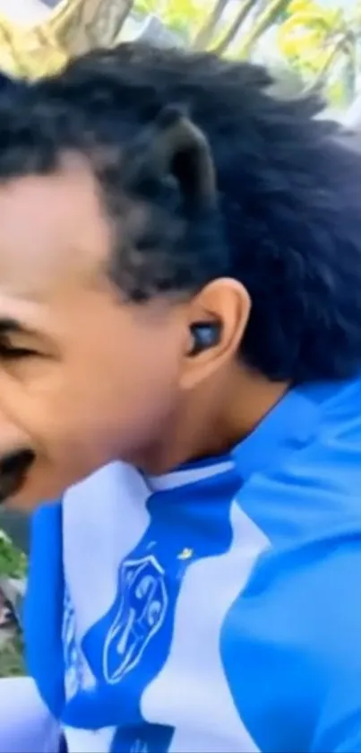 Man in blue outfit with unique hair outdoors.