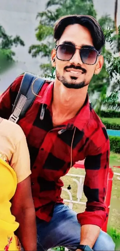 Outdoor selfie with vibrant attire and greenery in the background.