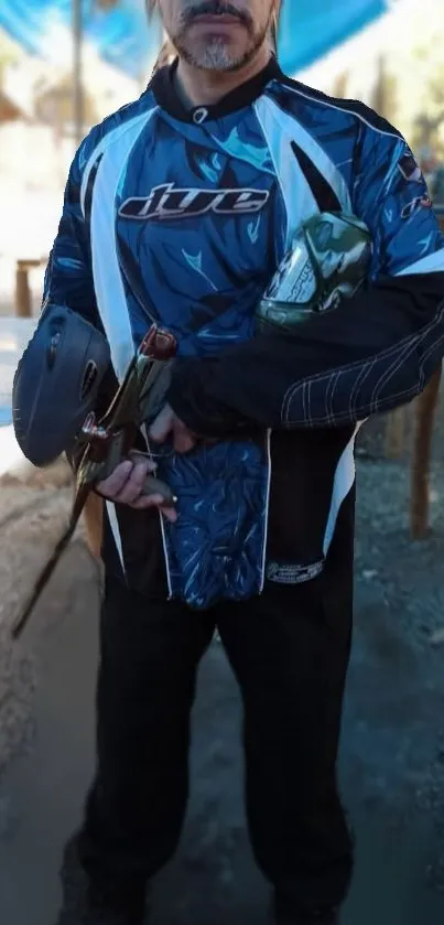 Paintball player in blue attire holding equipment.