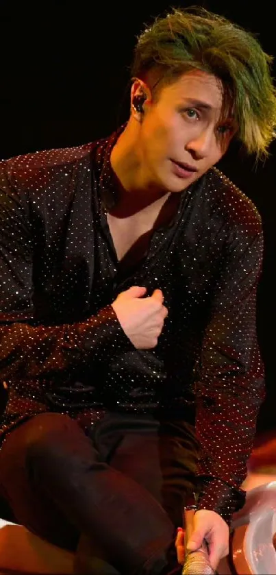 Dynamic performer in dark sparkly attire during a live concert performance.