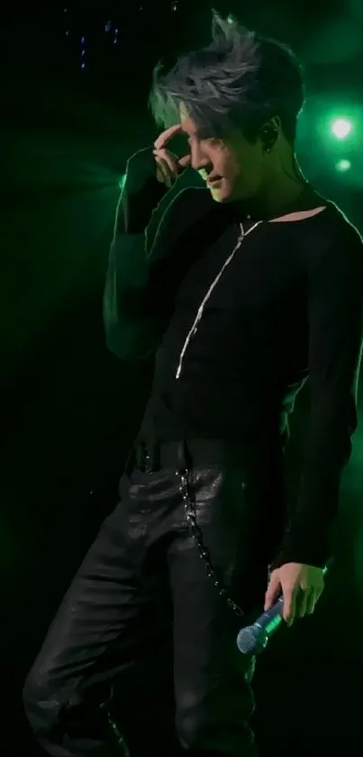 Energetic performer on stage with green lighting and black outfit.