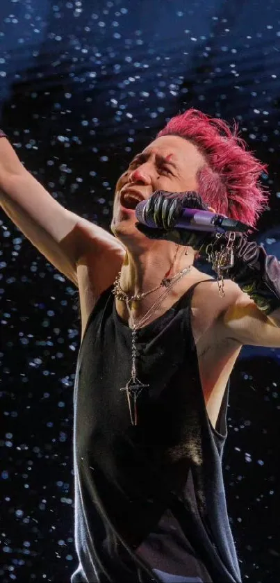 Performer with pink hair in dynamic pose on dark backdrop.